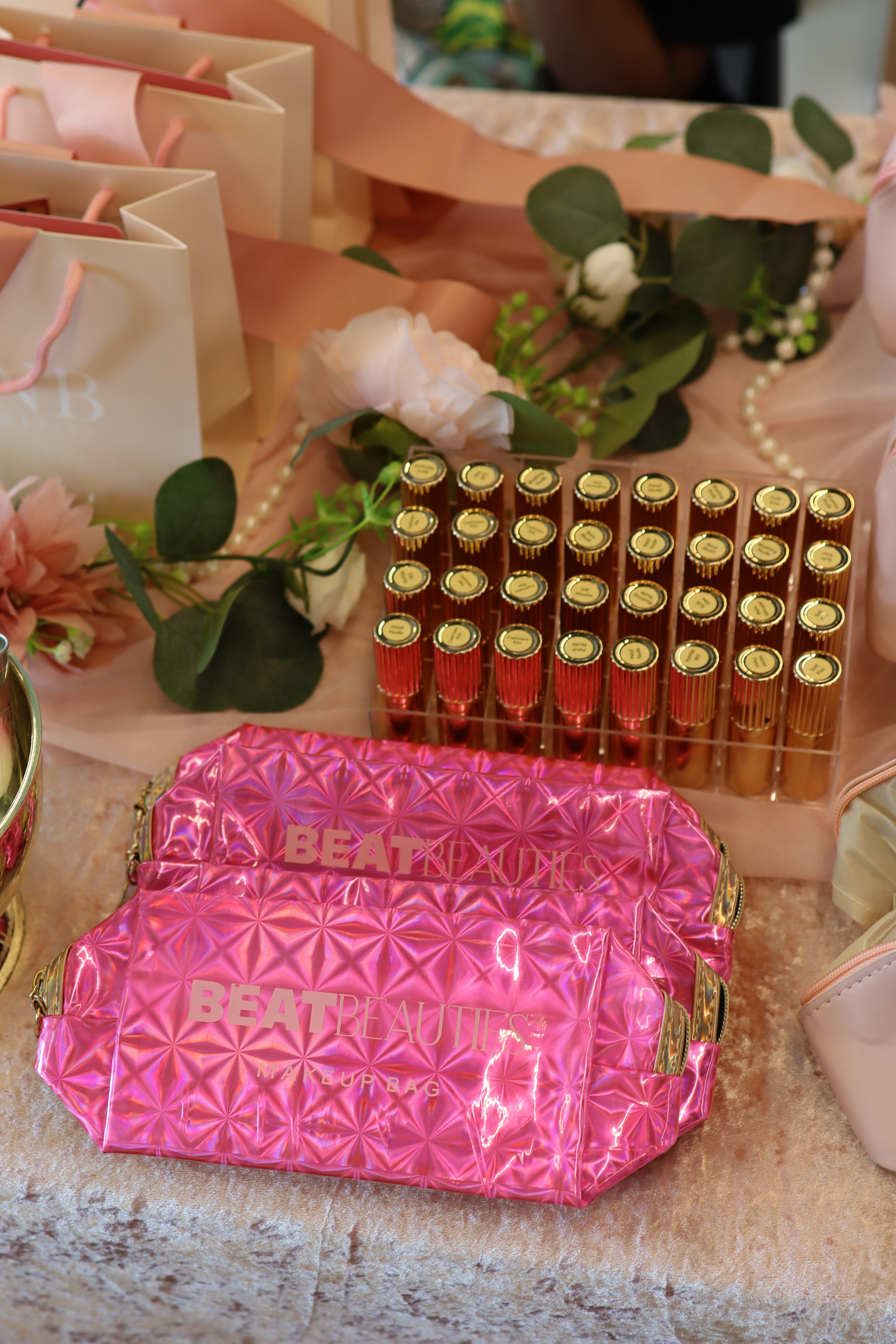 Pink holographic beauty bag with lipstick display and florals