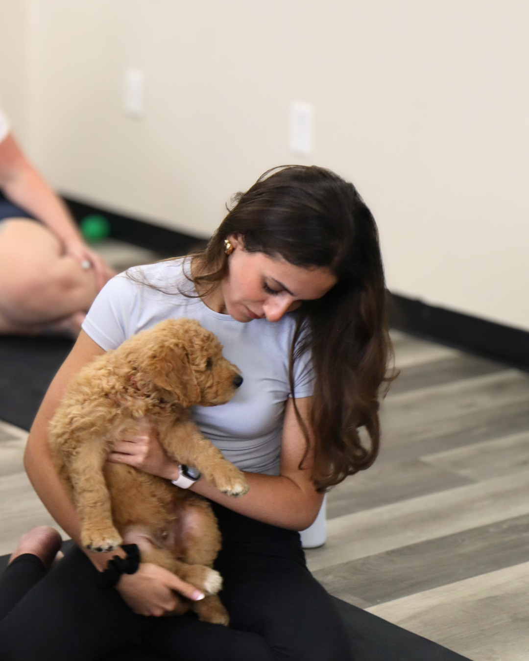 Woman holding a golden puppy at Puppy Paws Yoga
