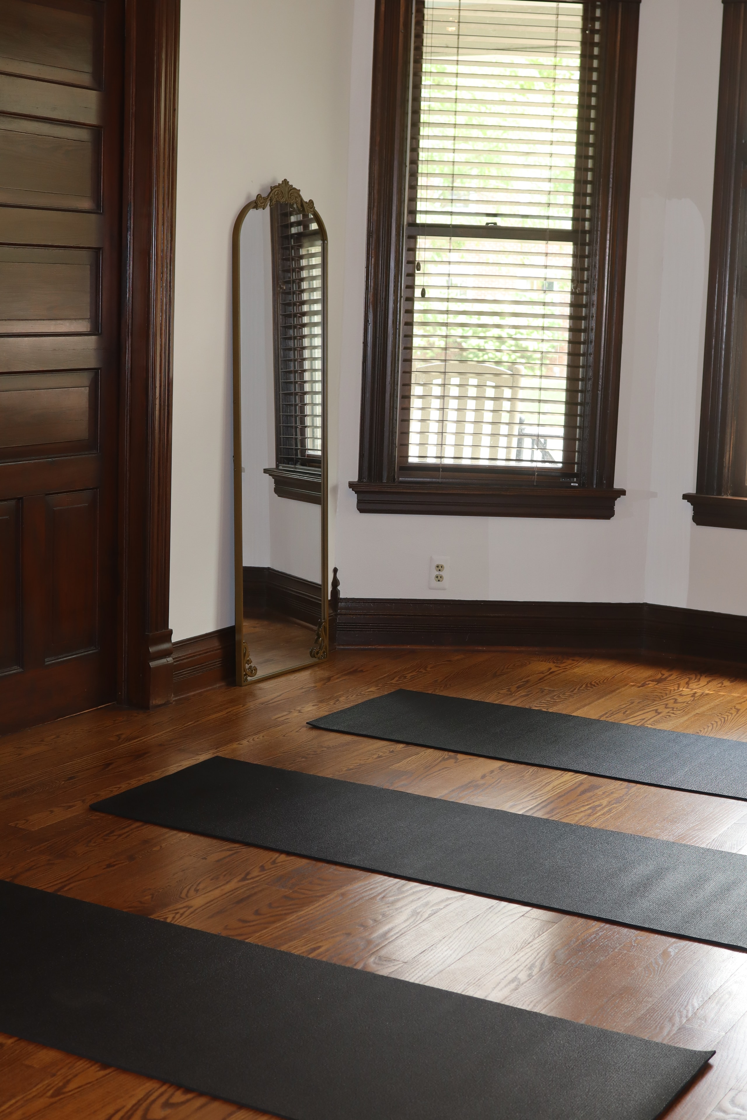 Yoga mats and gold mirror in hardwood studio space