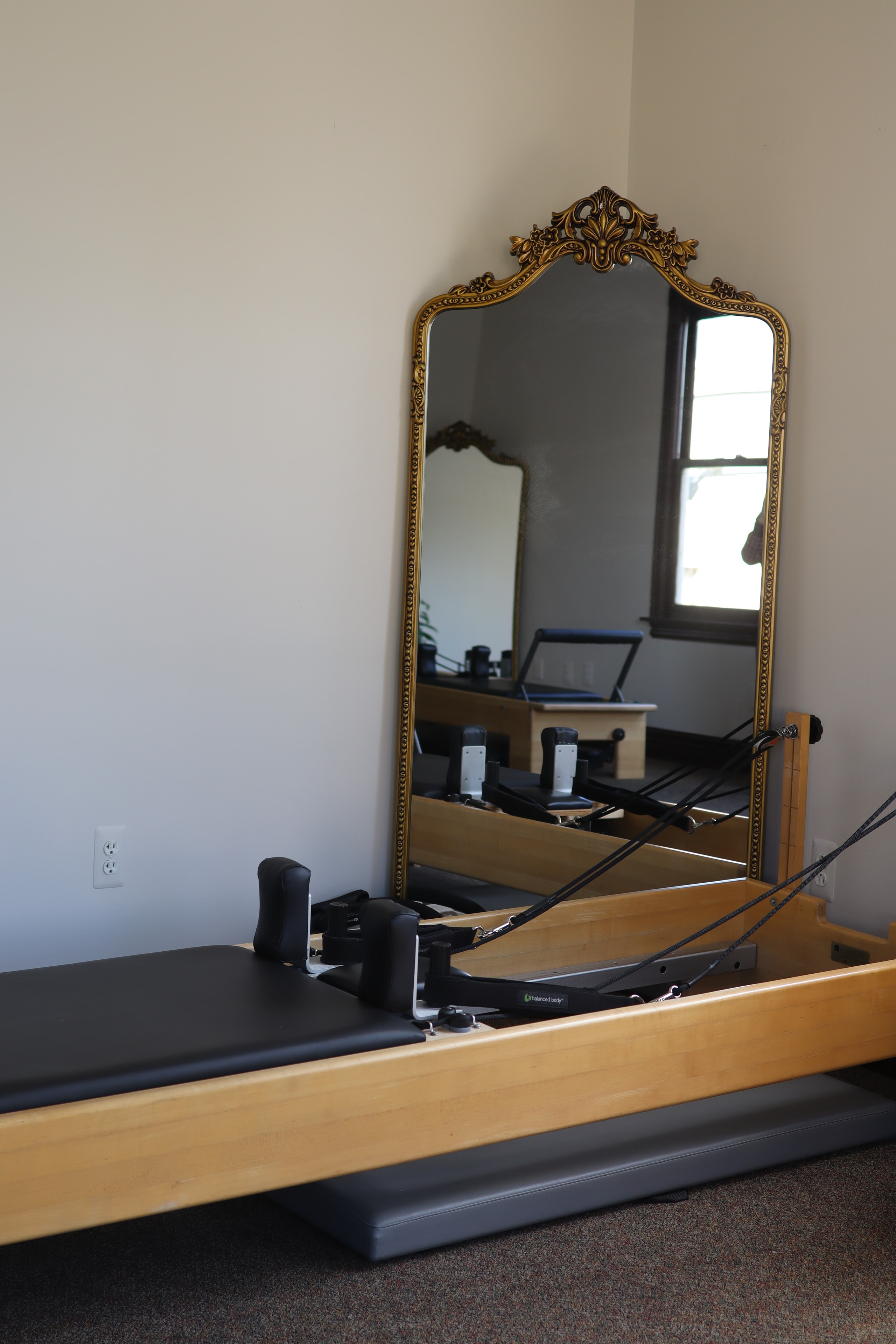 Pilates reformer footbar and carriage detail with gold mirror